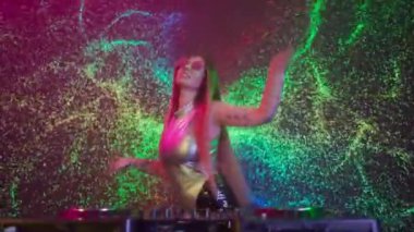 Gelecekçi siber punk teknolojisi konsepti. Dijital duvar renkli görsel arka planda çekici bir kadın. Genç kadın DJ dans ediyor, müzik karıştırıyor. Gece kulübünde piknik masaları karıştırıyor..