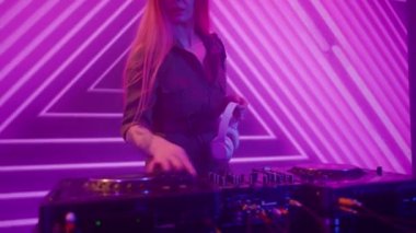 Gelecekçi siber punk teknolojisi konsepti. Dijital duvar renkli görsel arka planda çekici bir kadın. Genç kadın DJ dans ediyor, karıştırıyor ve pikaplarda müzik çalıyor. Gece kulübü partisinde..