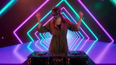 Gelecekçi siber punk teknolojisi konsepti. Dijital duvar renkli görsel arka planda çekici bir kadın. Maskeli genç kadın DJ dans ediyor, müzik karıştırıyor gece kulübünde pikaplarda müzik çalıyor..
