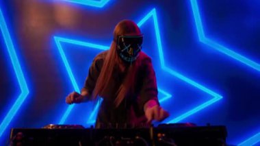 Gelecekçi siber punk teknolojisi konsepti. Dijital duvar renkli görsel arka planda çekici bir kadın. Maskeli genç kadın DJ dans ediyor, müzik karıştırıyor gece kulübünde pikaplarda müzik çalıyor..