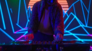 Gelecekçi siber punk teknolojisi konsepti. Dijital duvar renkli görsel arka planda çekici bir erkek. Maskeli genç adam dans ediyor, müzik karıştırıyor gece kulübünde pikaplarda müzik çalıyor..