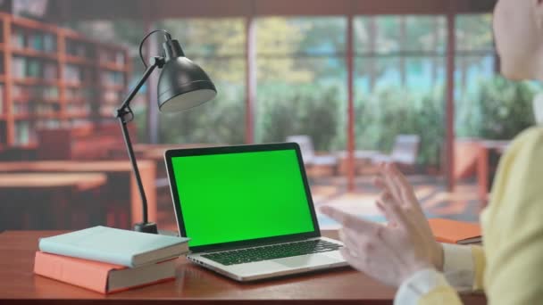 Žena Komunikuje Videohovoru Notebooku Zelenou Obrazovkou Teplé Pozadí Knihovny Okny — Stock video