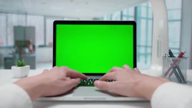 İşadamı yeşil ekranlı bir dizüstü bilgisayarda daktilo kullanıyor. Pencereleri olan parlak bir ofis. Metin veya resim için şablon yeri, promosyon içeriği. Reklam alanı, çalışma alanı maketi