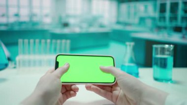 Akıllı telefon yeşil ekran krom anahtarıyla mesaj atan bir kadının elleri. Soğuk mavi laboratuvar geçmişi. Metin veya resim için şablon yeri, promosyon içeriği. Reklam alanı, çalışma alanı maketi.