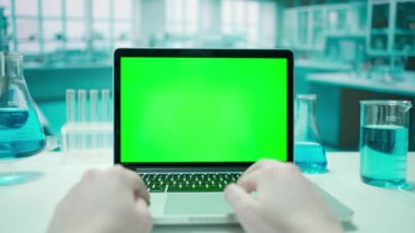 Yeşil ekran krom anahtarı olan bir dizüstü bilgisayarda çalışan kadın doktor. Soğuk mavi laboratuvar geçmişi. Metin veya resim için şablon yeri, promosyon içeriği. Reklam alanı.