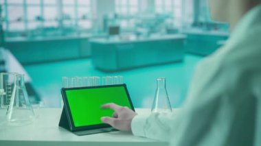 Bir kadının elleri tablet yeşil krom anahtar ekranla etkileşim halindedir. Soğuk mavi laboratuvar geçmişi. Metin veya resim için şablon yeri, promosyon içeriği. Reklam alanı, çalışma alanı maketi.