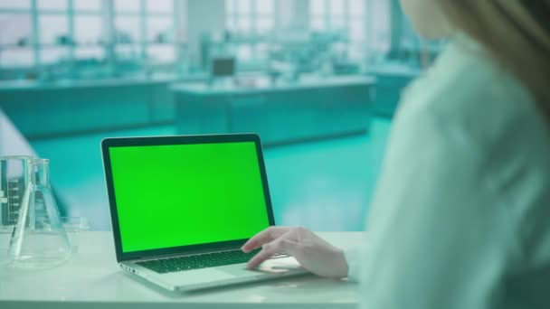 女性医師は緑色のクロマキーでラップトップに取り組んでいます コールドブルーラボの背景 テキストや画像 プロモーションコンテンツのテンプレート 広告エリア — ストック動画