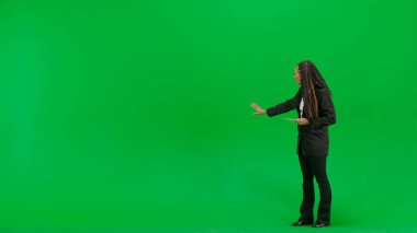 Televizyon haberleri ve canlı yayın konsepti. Genç bayan muhabir krom anahtar yeşil ekran arka planında izole edildi. Tam teşekküllü Afro-Amerikan kadın televizyon sunucusu elinde tablet, boş bir alan gösteriyor..