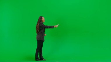 Televizyon haberleri ve canlı yayın konsepti. Genç bayan muhabir krom anahtar yeşil ekran arka planında izole edildi. Tam teşekküllü Afro-Amerikan kadın TV sunucusu mikrofon kullanarak röportaj yapıyor..