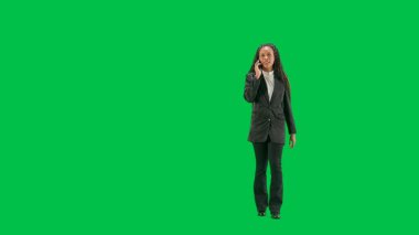 Televizyon haberleri ve canlı yayın konsepti. Genç bayan muhabir krom anahtar yeşil ekran arka planında izole edildi. Tam teşekküllü Afro-Amerikan kadın televizyon sunucusu akıllı telefondan konuşuyor ve yürüyor..