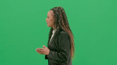 Televizyon haberleri ve canlı yayın konsepti. Genç bayan muhabir krom anahtar yeşil ekran arka planında izole edildi. Afrikalı Amerikalı kadın televizyon sunucusu yürüyor ve konuşuyor. Yan görünüm.