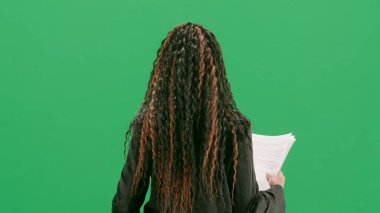 Televizyon haberleri ve canlı yayın konsepti. Genç bayan muhabir krom anahtar yeşil ekran arka planında izole edildi. Afrikalı Amerikalı kadın TV sunucusu konuşuyor ve gazete okuyor. Arka plan.