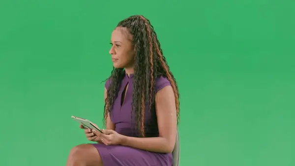 テレビニュースとライブ放送コンセプト クロマキーの緑色の背景に隔離されたドレスの女性 アフリカ系アメリカ人女性テレビニュースホスト 座ってタブレットを保持し インタビュー — ストック写真