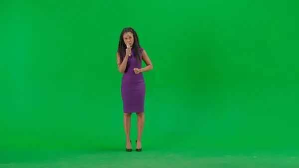 テレビニュースとライブ放送コンセプト クロマキーの緑色の背景に隔離されたドレスの女性 フルショット アフリカ系アメリカ人女性テレビニュースホスト立ってマイクでカメラを見ている — ストック写真