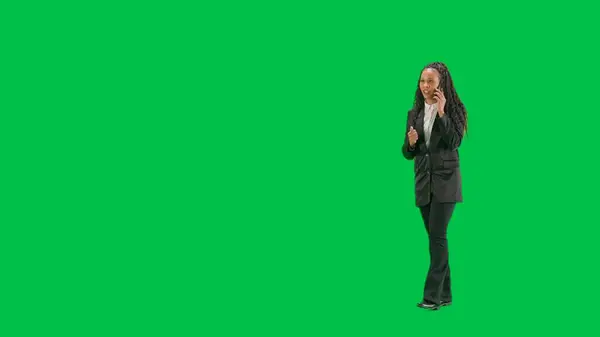 テレビニュースとライブ放送コンセプト クロマキーの緑色の背景に隔離された若い女性の記者は フルショット アフリカ系アメリカ人女性テレビニュースホスト 歩いてスマートフォンで話す ハーフターン — ストック写真