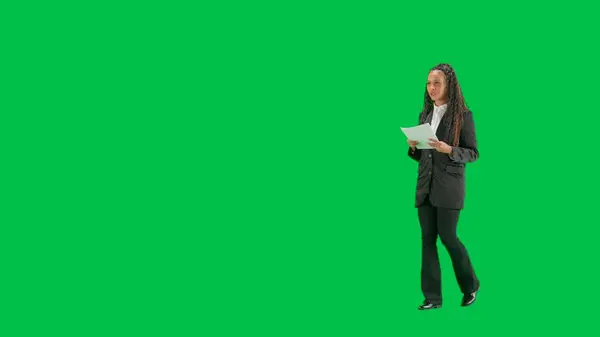 电视新闻和现场直播的概念 年轻的女记者在彩色键绿色屏幕背景上被隔离 全镜头非洲裔美国妇女电视新闻节目主持人走在谈话和阅读报纸 转半圈 — 图库照片