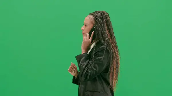 テレビニュースとライブ放送コンセプト クロマキーの緑色の背景に隔離された若い女性の記者は アフリカ系アメリカ人女性テレビのニュースホストがスマートフォンで歩いて話す サイドビュー — ストック写真