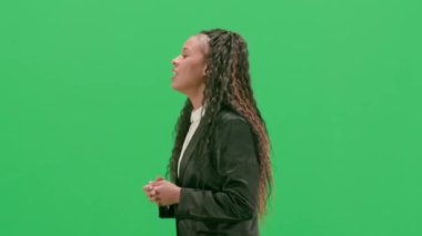 Televizyon haberleri ve canlı yayın konsepti. Genç bayan muhabir krom anahtar yeşil ekran arka planında izole edildi. Afrikalı Amerikalı kadın televizyon sunucusu yürüyor ve konuşuyor. Yan görünüm.