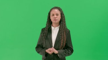 Televizyon haberleri ve canlı yayın konsepti. Genç bayan muhabir krom anahtar yeşil ekran arka planında izole edildi. Afrika kökenli Amerikalı kadın televizyon sunucusu ciddi bir suratla konuşuyor..