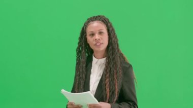Televizyon haberleri ve canlı yayın konsepti. Genç bayan muhabir krom anahtar yeşil ekran arka planında izole edildi. Afrika kökenli Amerikalı kadın televizyon sunucusu gazeteler konuşuyor ve yürüyor..