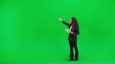 Televizyon haberleri ve canlı yayın konsepti. Genç bayan muhabir krom anahtar yeşil ekran arka planında izole edildi. Tam teşekküllü Afro-Amerikan kadın televizyon sunucusu elinde kağıtlarla kameraya bakıyor..