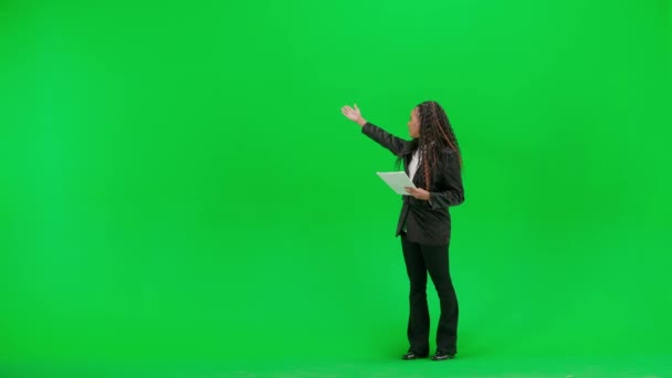 电视新闻和现场直播的概念 年轻的女记者在彩色键绿色屏幕背景上被隔离 全镜头非洲裔美国妇女电视新闻节目主持人 带着文件在镜头前交谈 — 图库视频影像