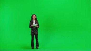 Televizyon haberleri ve canlı yayın konsepti. Genç bayan muhabir krom anahtar yeşil ekran arka planında izole edildi. Tam teşekküllü Afro-Amerikan kadın televizyon sunucusu. Gazeteler konuşuyor ve okuyor..