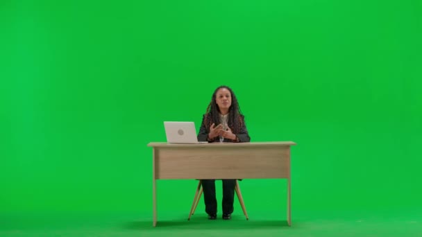 电视新闻和现场直播的概念 女性记者在办公桌上被隔离在彩色键绿色屏幕背景上 全速拍摄的非洲裔美国妇女电视新闻节目主持人坐在那里看着摄像机 — 图库视频影像