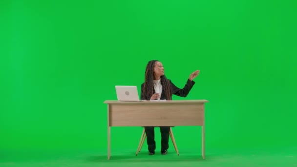 电视新闻和现场直播的概念 女性记者在办公桌上被隔离在彩色键绿色屏幕背景上 全镜头非洲裔美国女电视新闻主持人坐在网上与记者交谈 — 图库视频影像