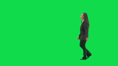 Televizyon haberleri ve canlı yayın konsepti. Genç bayan muhabir krom anahtar yeşil ekran arka planında izole edildi. Tam teşekküllü Afro-Amerikan kadın TV sunucusu yürüyüşü. Yan görünüm.
