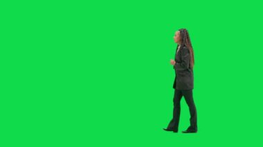 Televizyon haberleri ve canlı yayın konsepti. Genç bayan muhabir krom anahtar yeşil ekran arka planında izole edildi. Tam teşekküllü Afro-Amerikan kadın televizyon sunucusu yürüyüp konuşuyor. Yan görünüm.