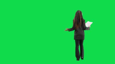 Televizyon haberleri ve canlı yayın konsepti. Genç bayan muhabir krom anahtar yeşil ekran arka planında izole edildi. Tam teşekküllü Afro-Amerikan kadın TV sunucusu konuşuyor ve gazete okuyor. Arka plan