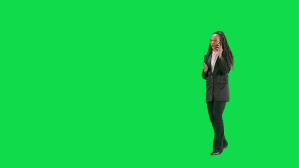 テレビニュースとライブ放送コンセプト クロマキーの緑色の背景に隔離された若い女性の記者は フルショット アフリカ系アメリカ人女性テレビニュースホスト 歩いてスマートフォンで話す ハーフターン — ストック動画