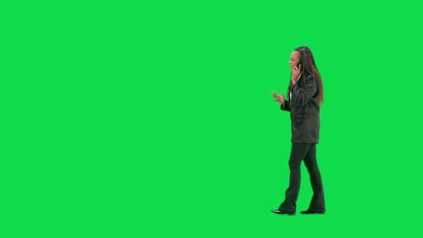 テレビニュースとライブ放送コンセプト クロマキーの緑色の背景に隔離された若い女性の記者は フルショット アフリカ系アメリカ人女性テレビニュースホスト 歩いてスマートフォンで話す サイドビュー — ストック動画