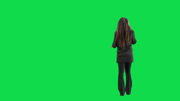 テレビニュースとライブ放送コンセプト クロマキーの緑色の背景に隔離された若い女性の記者は フルショット アフリカ系アメリカ人女性テレビニュースホスト 歩いてスマートフォンで話す バックビュー — ストック動画