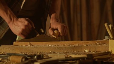 Marangozluk ve el işi reklam konsepti. Garajda çalışan erkek marangoz. Profesyonel marangoz, atölyede ahşap malzemelerle çalışıyor..