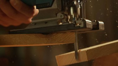 Marangozluk ve el işi reklam konsepti. Garajda çalışan erkek marangoz. Profesyonel marangoz atölyede yapboz kullanarak ahşap malzemelerle çalışıyor..