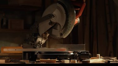 Marangozluk ve el işi reklam konsepti. Garajda çalışan erkek marangoz. Atölyede ahşap malzemelerle çalışan profesyonel marangoz uzmanı. Tahta kesmek için testere kullanıyor..