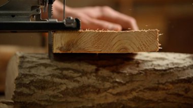 Marangozluk ve el işi reklam konsepti. Garajda çalışan erkek marangoz. Profesyonel marangoz atölyede yapboz kullanarak ahşap malzemeler üzerinde çalışıyor..