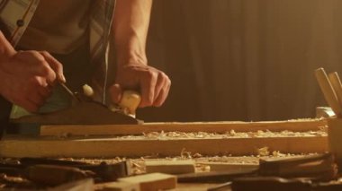 Marangozluk ve el işi reklam konsepti. Garajda çalışan erkek marangoz. Profesyonel marangoz, atölyede ahşap malzemelerle çalışıyor..