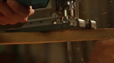 Marangozluk ve el işi reklam konsepti. Garajda çalışan erkek marangoz. Profesyonel marangoz atölyede yapboz kullanarak ahşap malzemelerle çalışıyor..