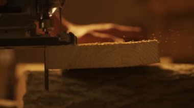 Marangozluk ve el işi reklam konsepti. Garajda çalışan erkek marangoz. Profesyonel marangoz atölyede yapboz kullanarak ahşap malzemeler üzerinde çalışıyor..