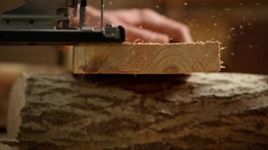 Marangozluk ve el işi reklam konsepti. Garajda çalışan erkek marangoz. Profesyonel marangoz atölyede yapboz kullanarak ahşap malzemeler üzerinde çalışıyor..