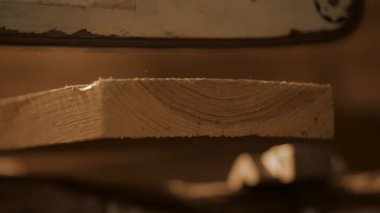 Marangozluk ve el işi reklam konsepti. Garajda çalışan erkek marangoz. Profesyonel marangoz, atölyede elektrikli testere kullanarak ahşap kesiyor..