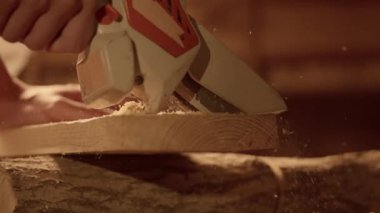 Marangozluk ve el işi reklam konsepti. Garajda çalışan erkek marangoz. Profesyonel marangoz atölyede malzemelerle çalışıyor. Kablosuz testereyle odun kesiyor. Kapatın..