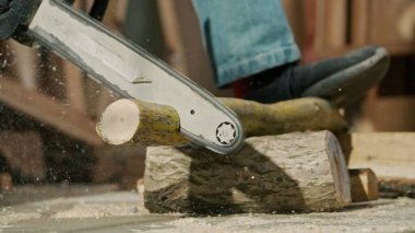 Marangozluk ve el işi reklam konsepti. Garajda çalışan erkek marangoz. Profesyonel marangoz, atölyede ahşap malzemelerle çalışıyor elektrikli testere kullanarak tahta kesiyor..