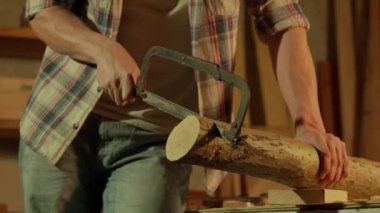 Marangozluk ve el işi reklam konsepti. Garajda çalışan erkek marangoz. Profesyonel marangoz atölyede ahşap malzemelerle çalışıyor. Yapboz kullanarak odun kesiyor..