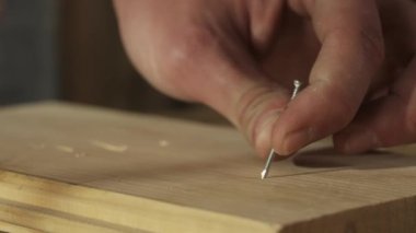 Marangozluk ve el işi reklam konsepti. Garajda çalışan erkek marangoz. Profesyonel marangoz atölyede ahşap malzemelerle çalışıyor ve tahta panele çivi çakıyor..