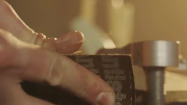 Marangozluk ve el işi reklam konsepti. Garajda çalışan erkek marangoz. Profesyonel marangoz atölyede ahşap malzemelerle çalışıyor zımpara kağıdıyla ahşap paneli zımparalıyor..