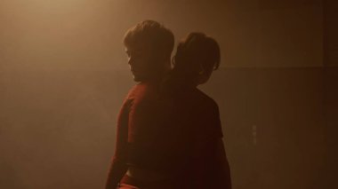 Deneysel koreografi dans stili konsepti. Profesyonel dansçılar dans gösterisi yapıyor. Genç erkek ve kadın dansçılar modern koreografi elementlerini dumanla, orta çekimde sergiliyorlar..